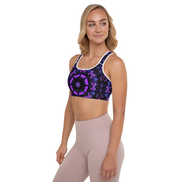 Photograph of a model wearing Bleace MetaParty Vibes Kaleidoscopic purple, blue, and pink, Trippy Visual sports bra in the foreground with a white background.  