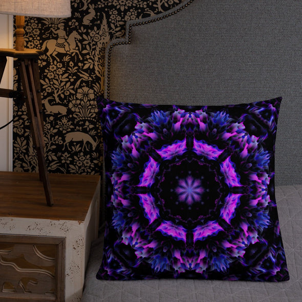 Photograph of a model wearing Bleace unisex MetaParty Vibes Kaleidoscopic purple, blue, and pink, Trippy Visual pillow placed on a chair in the foreground with a grey wall background.  