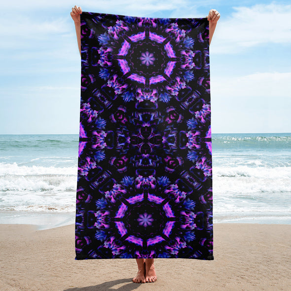 Photograph of a model wearing Bleace unisex MetaParty Vibes Kaleidoscopic purple, blue, and pink, Trippy Visual towel in the foreground with a beach background.  